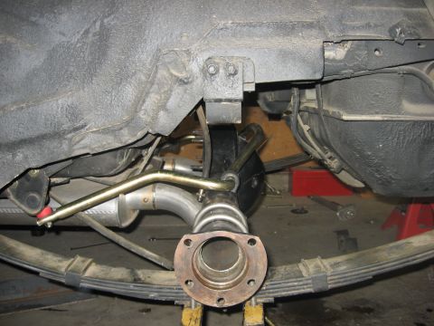 1978 Ford Mustang II - Underside view of a rear leaf-spring live axle on a car up on jack stands, showing the bare axle-tube flange with wheel studs removed, the…