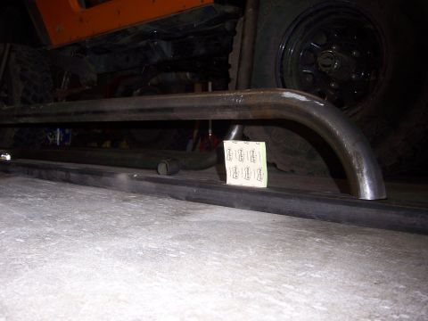 1991 Ford Bronco - Custom metal rock sliders are attached to the undercarriage of an orange off-road vehicle.