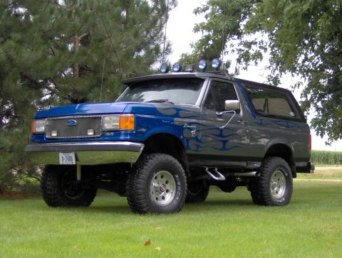 1987 Ford Bronco - This lifted Ford Bronco has custom flame graphics and a light bar on its roof visor.