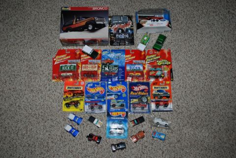 1996 Ford Bronco - A variety of toy vehicles and model kits are displayed on a carpeted surface.