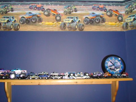 1979 Ford Bronco - Toy monster trucks are displayed on a shelf under wallpaper depicting monster trucks in action.