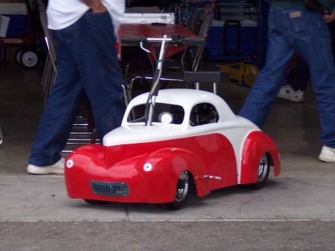 1972 Ford Ranchero - A small, two-tone toy car with a retro design is pushed by unseen individuals.