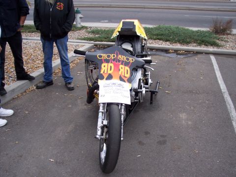 1972 Ford Ranchero - A custom drag motorcycle with flames and text is parked in a lot, with people standing nearby.