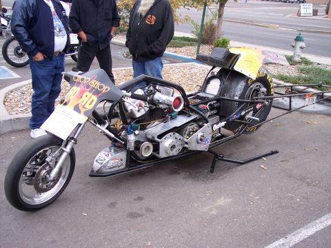 1972 Ford Ranchero - A custom drag racing motorcycle with a prominent engine and large rear tire is displayed, with people standing nearby.