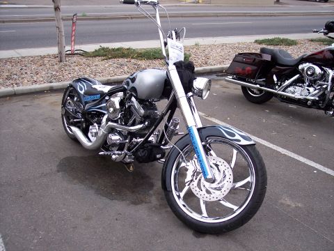 1972 Ford Ranchero - A custom chopper motorcycle with flame graphics and large chrome wheels is parked in a lot, with another motorcycle visible behind it.