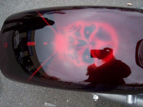 1972 Ford Ranchero - A close-up of a motorcycle fender features a red airbrushed skull design, with reflections of the photographer and surroundings visible on…