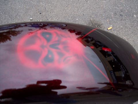 1972 Ford Ranchero - A close-up of a car hood shows a red airbrushed skull design with reflections of a building.