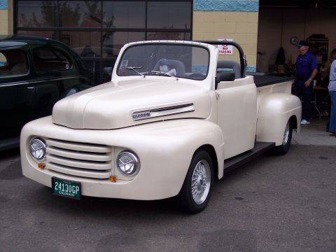 1972 Ford Ranchero - This cream-colored convertible pickup truck, possibly a 1950 Ford F-series, is parked next to another vehicle.