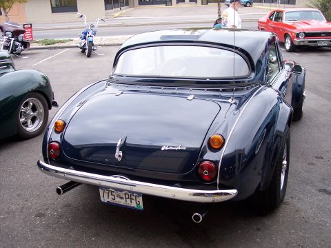 1972 Ford Ranchero - A dark blue convertible is parked in a lot, showing its rear end with a chrome bumper and dual exhaust pipes.