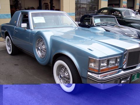 1972 Ford Ranchero - A light blue coupe with whitewall tires and a spare tire mounted on the fender is parked next to another vehicle.