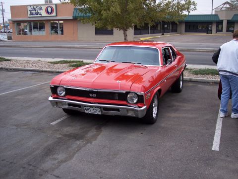 1972 Ford Ranchero - A red coupe with SS badging is parked in a lot next to a laundry business.