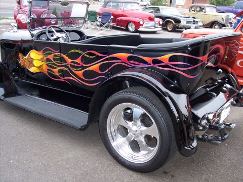 1972 Ford Ranchero - A black hot rod with vibrant flame graphics is parked among other classic cars.