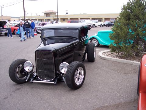 1972 Ford Ranchero - A black hot rod coupe is parked at a car show, with other vehicles visible in the background.