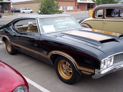 1972 Ford Ranchero - A black and gold 1970 Oldsmobile 442 is parked next to another classic car.