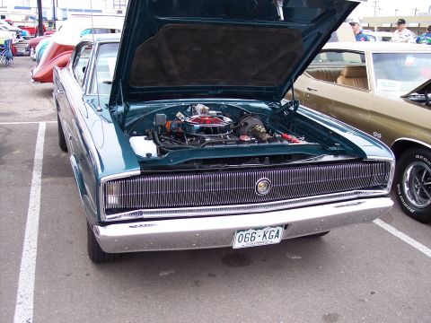 1972 Ford Ranchero - A teal 1967 Dodge Charger is displayed with its hood open, the engine and front grille. Another classic car is parked nearby.