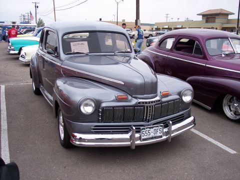 1972 Ford Ranchero - A gray 1947 Mercury coupe is parked at a car show, with a purple car visible to its right.