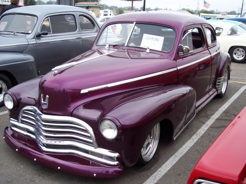 1972 Ford Ranchero - A custom purple coupe hot rod is parked next to other vehicles at a show.