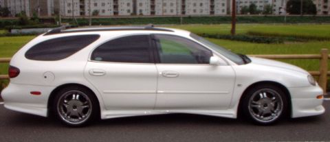 1996 Ford Taurus - Side view of a white station wagon with custom wheels and body kit.