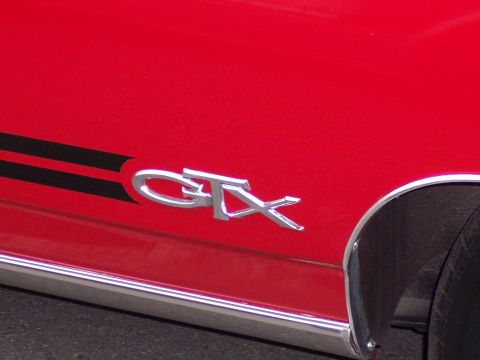 1972 Ford Ranchero - A chrome GTX badge is visible on the side of a red vehicle with black racing stripes.