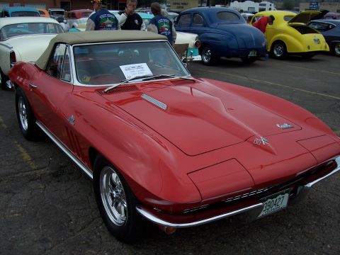 1972 Ford Ranchero - A bright red 1965 Corvette convertible is displayed at a car show, with other vehicles visible in the background.