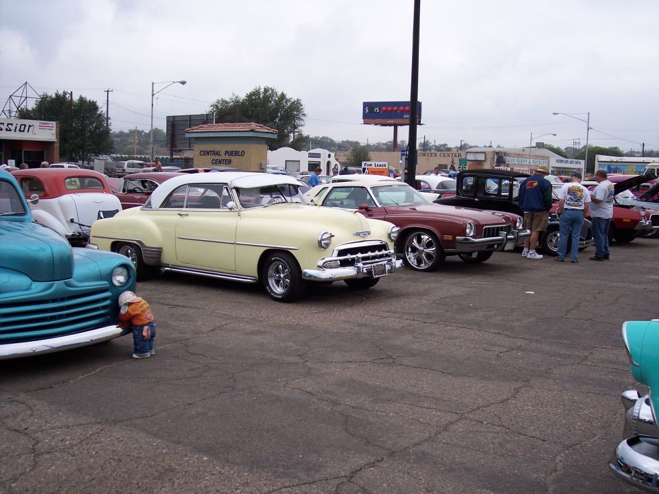 Yellow and white 1951 Chevrolet coupe with chrome accents parked at a car show