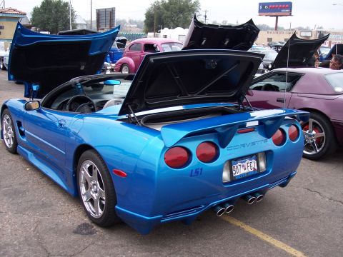 1972 Ford Ranchero - A bright blue convertible Corvette with its hood and trunk open is parked at a show, with other vehicles visible in the background.