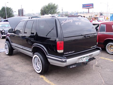 1972 Ford Ranchero - A black Chevrolet Blazer with custom whitewall tires and chrome rims is parked next to another vehicle.