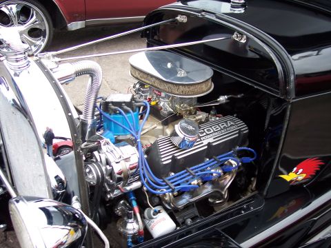 1972 Ford Ranchero - The engine bay of a custom hot rod features a prominent V8 engine with performance upgrades and decorative elements.