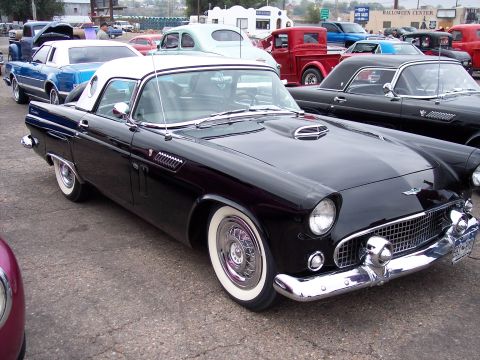 1972 Ford Ranchero - A classic black 1955 Ford Thunderbird is parked at a car show, its distinctive body style and whitewall tires catching the eye.