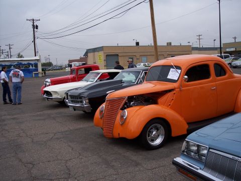 1972 Ford Ranchero - Several classic cars are lined up in a parking lot under an overcast sky.
