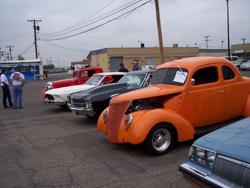Orange coupe hot rod with hood open, parked in a lot with other cars