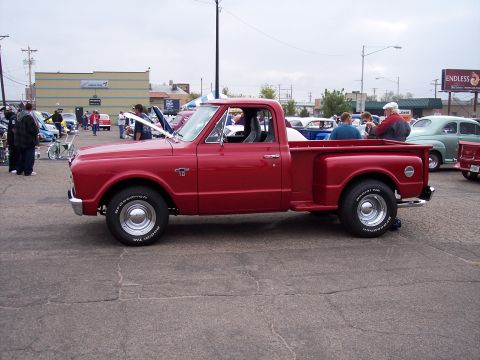 1972 Ford Ranchero - A red pickup truck is parked at an outdoor event with other vehicles visible in the background.
