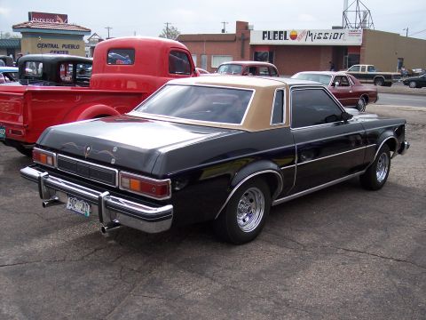 1972 Ford Ranchero - A black Ford Fairmont Futura coupe is parked on asphalt, with a red pickup truck and other vehicles in the background.