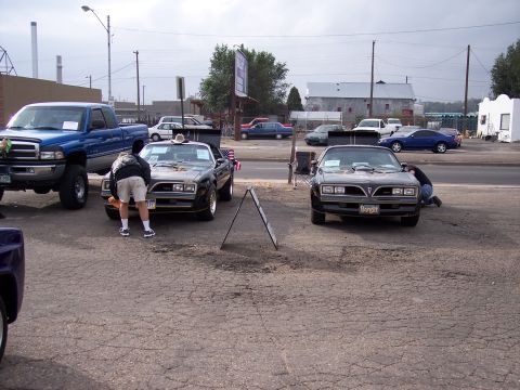 1972 Ford Ranchero - Two black Pontiac Firebirds are displayed, with one having a person attending to its front end.