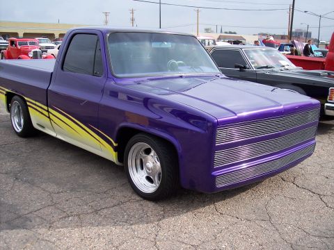 1972 Ford Ranchero - Customized purple pickup truck with racing stripes and a unique front grille is parked at a car show.