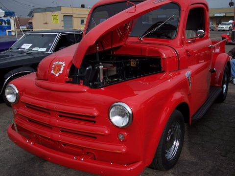 1972 Ford Ranchero - A bright red pickup truck is displayed with its hood up, revealing the engine compartment.