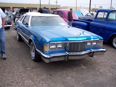 1972 Ford Ranchero - A blue 1977 Mercury Cougar coupe with a white roof is parked at an outdoor event with other vehicles.