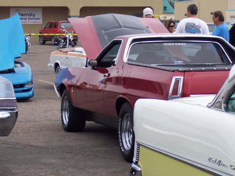 1972 Ford Ranchero - A maroon Ford Ranchero is parked at a car show with its hood up, alongside other cars.