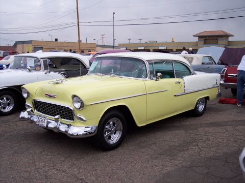1972 Ford Ranchero - A two-tone yellow and white 1955 Chevrolet Bel Air coupe is displayed at a car show, with other vehicles visible in the background.