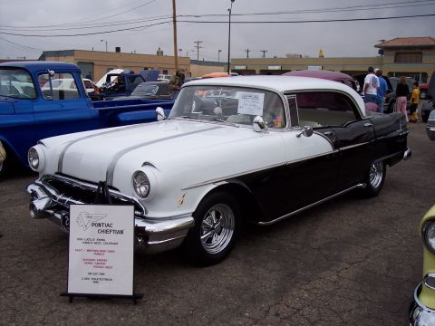 1972 Ford Ranchero - Two-tone 1956 Pontiac Chieftain on display at a car show, with a blue truck nearby.