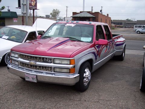 1972 Ford Ranchero - Customized dually pickup truck with flame grille and patriotic graphics parked next to another vehicle.
