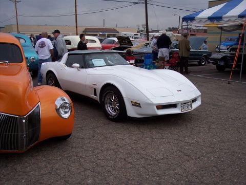1972 Ford Ranchero - White Chevrolet Corvette with T-tops at a car show, parked next to an orange 1940s Ford coupe.