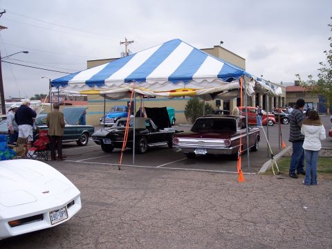 1972 Ford Ranchero - Several classic cars are displayed under a large tent at an outdoor gathering, with a white Corvette in the foreground.