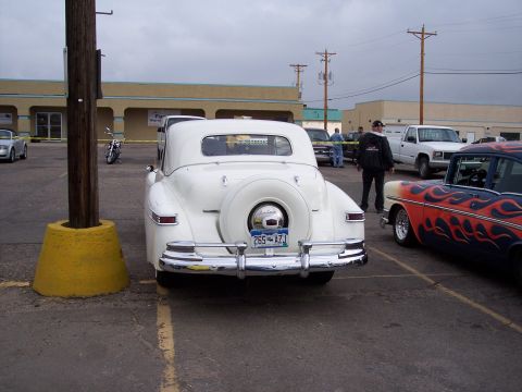 1972 Ford Ranchero - A white convertible with a spare tire mounted on the rear is parked next to a car with flame graphics.