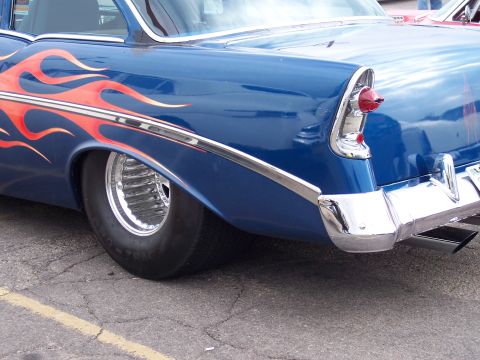1972 Ford Ranchero - The rear fender and chrome bumper of a blue hot rod with flame decals are visible.