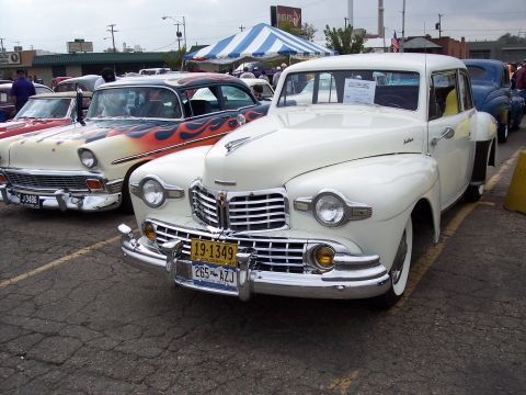 1972 Ford Ranchero - A white sedan with a distinctive chrome grille and dual headlights is parked at a car show.
