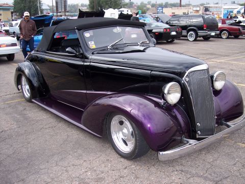 1972 Ford Ranchero - A custom black convertible with purple accents is displayed at an outdoor event with other vehicles in the background.
