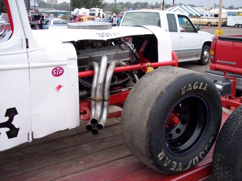1972 Ford Ranchero - Custom race car on a trailer, showing its engine and large racing tire. Other vehicles and tents are in the background.