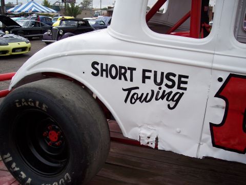 1972 Ford Ranchero - A white stock car with "SHORT FUSE Towing" painted on its side is parked outdoors with other vehicles visible in the background.