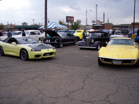 1972 Ford Ranchero - A yellow sports car is parked in a lot with several other vehicles, including a classic Corvette.